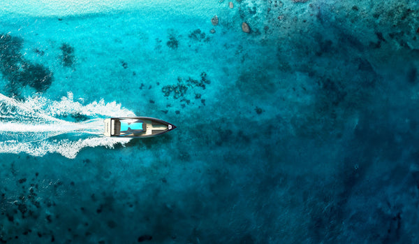 Aerial image the VOLTARI 260 in Ballistic Charcoal and Miami blue, riding over clear tropical ocean waters
